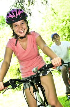 Teenage girl and her father riding bicycles in summer park