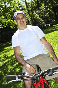 Happy middle aged man riding a bicycle in summer part