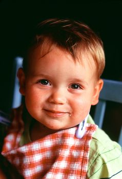 smiling todler with checked bib at meal time