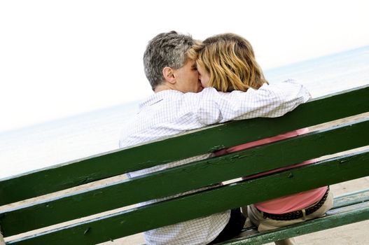 Mature romantic couple on a bench on seashore