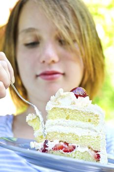 Teenage girl eating a piece of strawberry cake