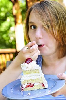 Teenage girl eating a piece of strawberry cake