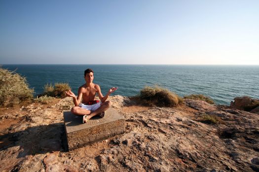 sexy man doing yoga on the coast