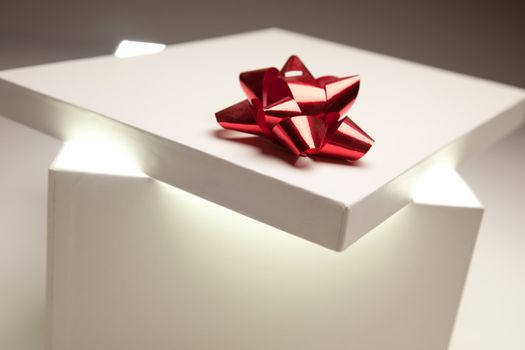 Gift Box with Red Bow Lid Revealing Very Bright Contents on a Gradated Background.