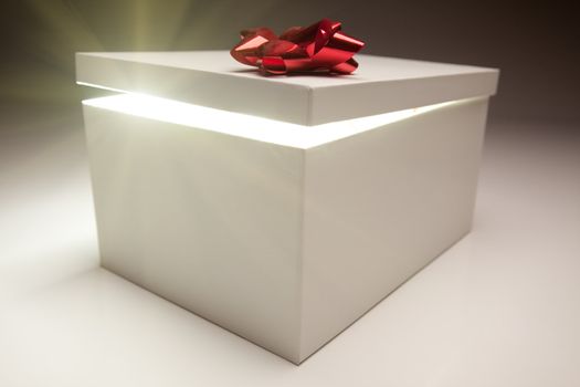 Gift Box with Red Bow Lid Revealing Very Bright Contents on a Gradated Background.
