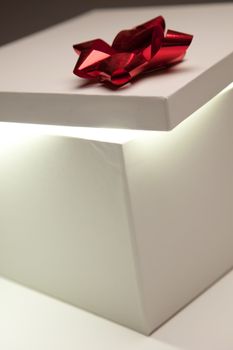 Gift Box with Red Bow Lid Revealing Very Bright Contents on a Gradated Background.