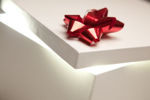 Gift Box with Red Bow Lid Revealing Very Bright Contents on a Gradated Background.