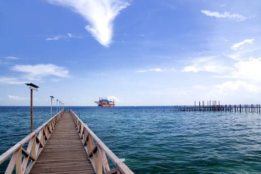 Image of a jetty against a backdrop of a beautiful sea, sky and an oil rig in Malaysia.