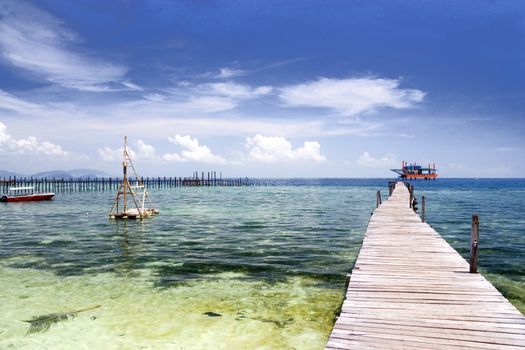 Image of a jetty against a backdrop of a beautiful sea, sky and an oil rig in Malaysia.