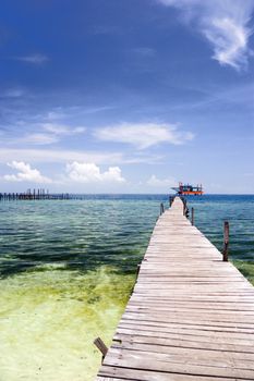 Image of a jetty against a backdrop of a beautiful sea, sky and an oil rig in Malaysia.