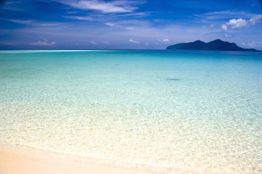 Image of a remote Malaysian tropical island beach with deep blue skies and crystal clear waters.