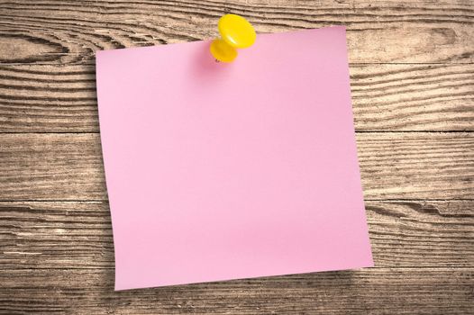 Pink paper note with thumbtack on wooden surface, clipping path.