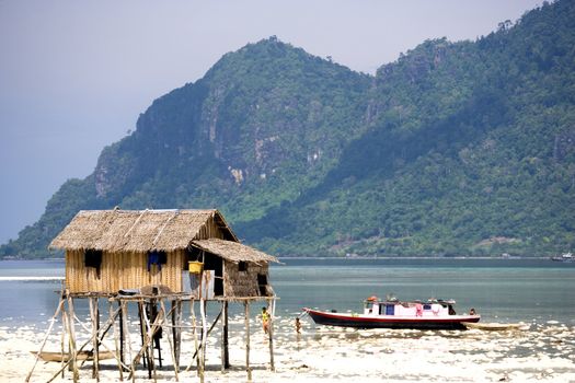 Image of an island native hut on stilts and a house boat.