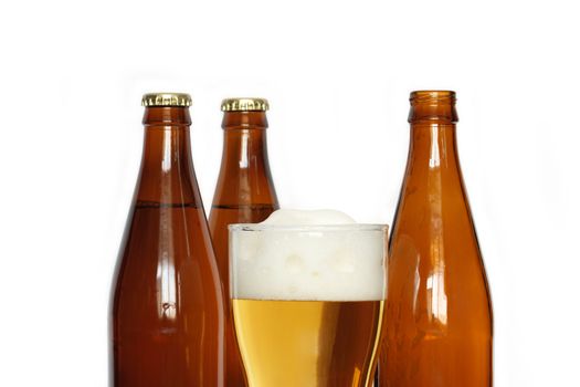 Closeup of beer glass near three bottles isolated on white background 