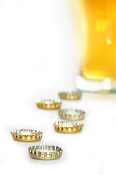 Few bottle caps on white background with beer glass