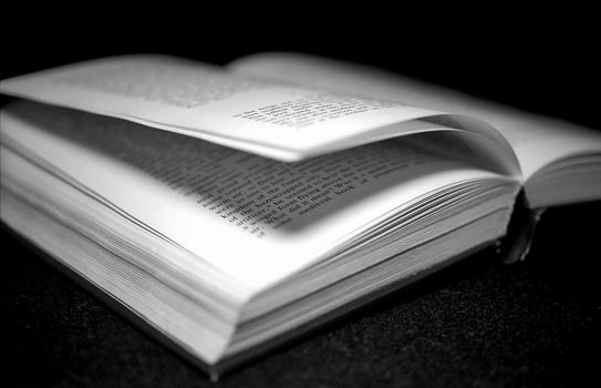 Open book on black background monochrome