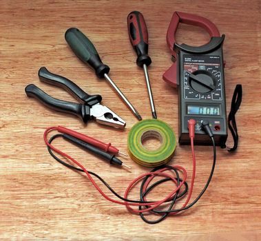 Digital clamp meter instrument and electrician tools on wooden surface