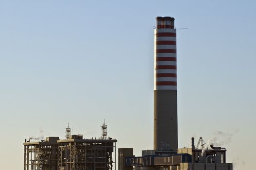View of a power plant with an high chimney at sunrise