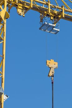 Detail of yellow crane with hook against a blue sky
