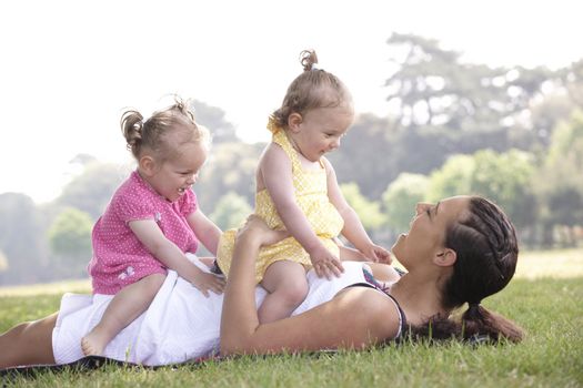 mother playing with daughters in the park in summer