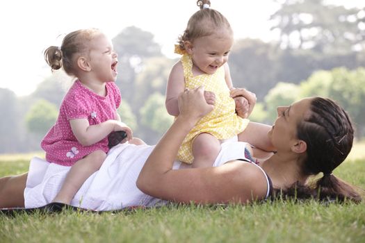 mother playing with daughters in the park in summer