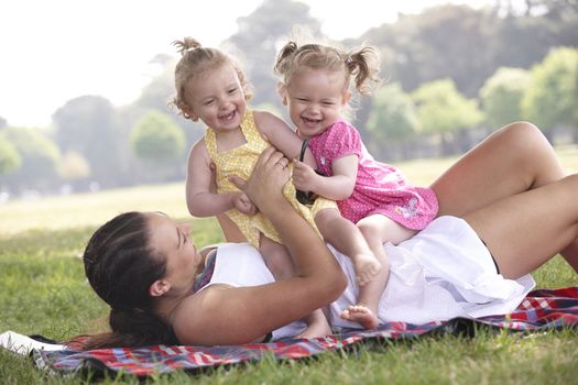 mother playing with daughters in the park in summer