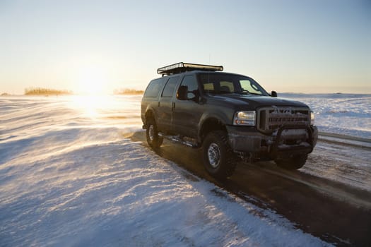 Truck on icy road with snowy landscape.