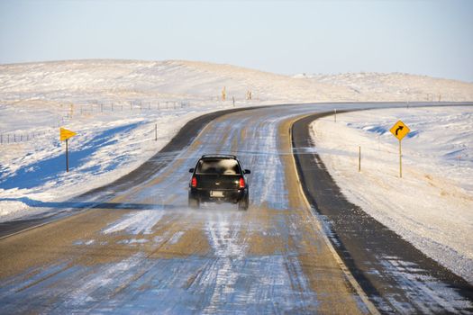 SUV on icy road in snowy landscape.