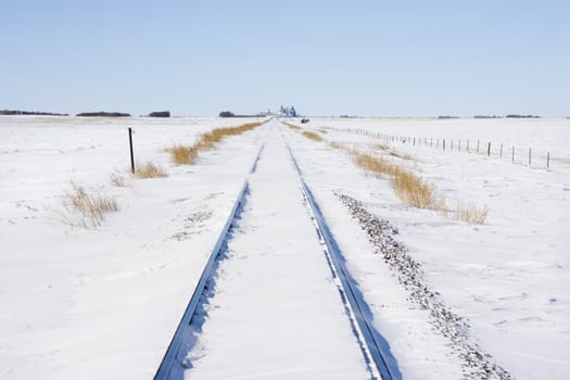 Railroad tracks in snow covered rural landscape.
