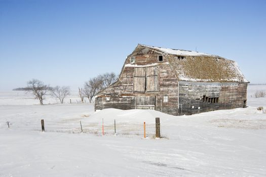 Rustic barn in rural snow covered landscape.