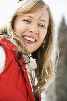 Portrait of attractive smiling mid adult Caucasian blond woman wearing red ski vest looking at viewer.