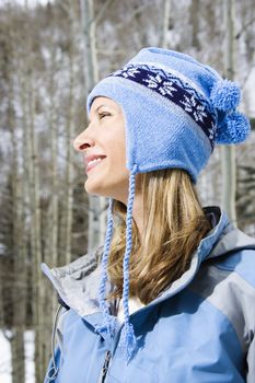 Side view head and shoulder of attractive smiling mid adult Caucasian blond woman wearing blue ski clothing.