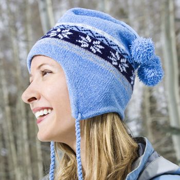 Side view headshot of attractive smiling mid adult Caucasian blond woman wearing blue ski cap.