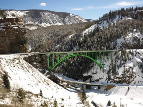 Mountain landscape with bridge crossing over roadway.