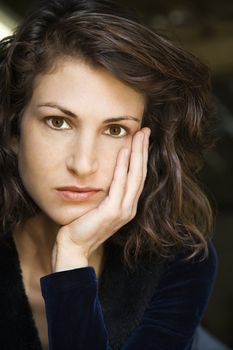 Portrait of pretty mid adult Caucasian woman with head on hand making eye contact.