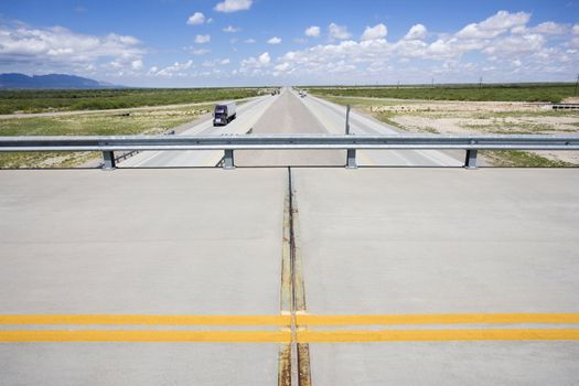 Overpass with highway below with tractor trailer truck.