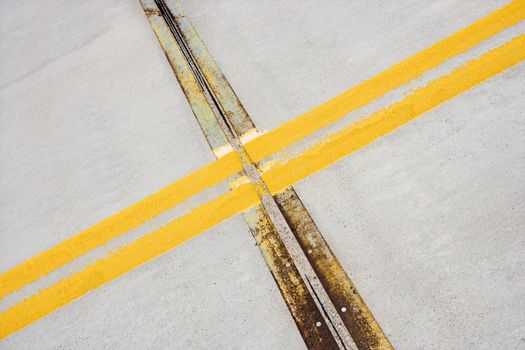 Detail of solid double yellow line in road crossing metal strips in cement.