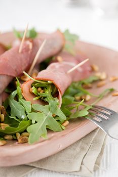 Rolls with raw ham filled with garden rocket salad and pineseeds
