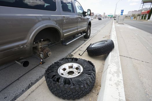 Vehicle brokendown along roadside with damaged tire needing replacement.