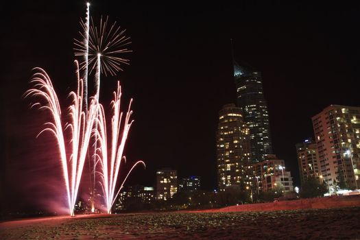 Night firework display exploding with Surfers Paradise city skyline in Australia.