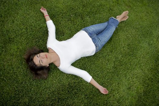 Beautiful young woman lying on the grass 