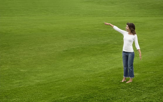 Woman on a beautiful green meadow showing something