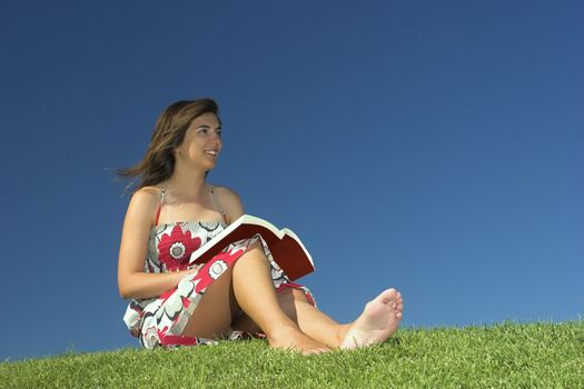 Beautiful woman reading a book on a green meadow