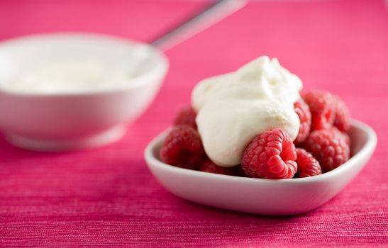 Small bowl filled with raspberries and whipped cream