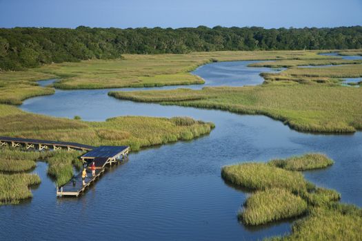 Aerial view of two teenage boys fishing from dock in marshy lowlands of Bald Head Island, North Carolina.