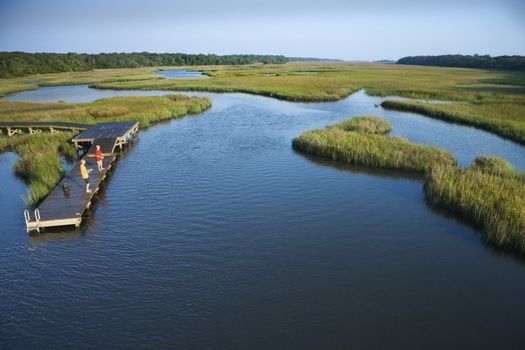 Aerial view of two teenage boys fishing from dock in marshy lowlands of Bald Head Island, North Carolina.