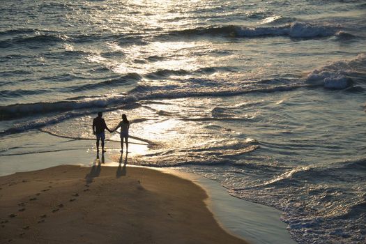 Aerial view of couple holding hands on beach in Bald Head Island, North Carolina at sunset.