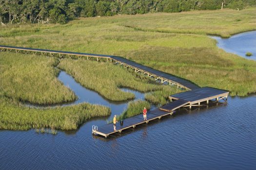 Aerial view of two teenage boys fishing from dock in marshy lowlands of Bald Head Island, North Carolina.