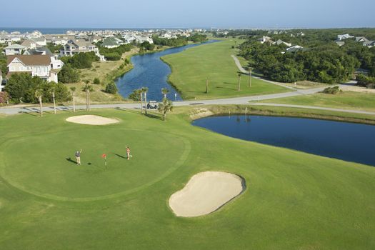 Aerial view of two people palying golf near residential community at Bald Head Island, North Carolina.