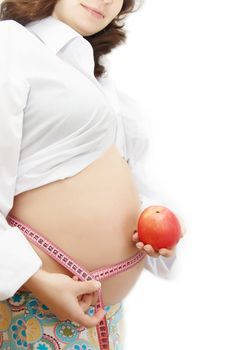 woman holding pregnant belly with measuring tape and red apple